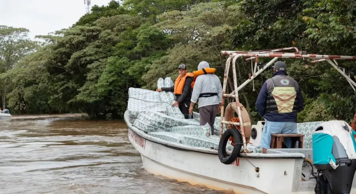 Una embarcación traslada colchones protegidos con plástico y a tripulantes con chalecos salvavidas por las aguas cercanas a la Isla Apipé. - Infobae